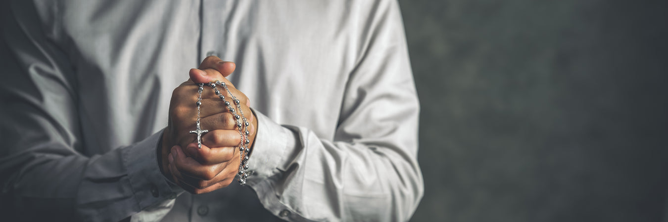 Man holding a rosary in prayer